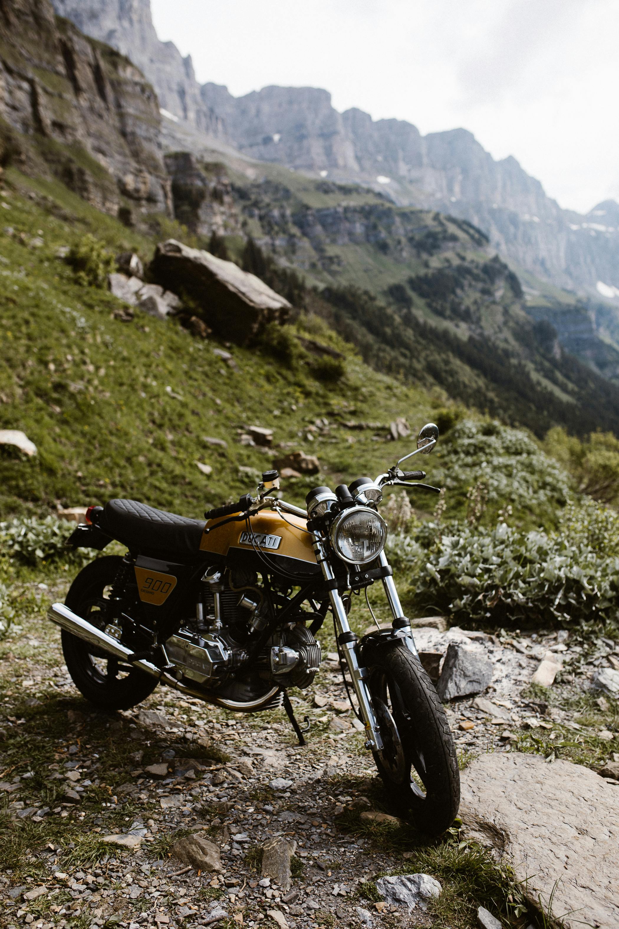A classic Ducati motorcycle parked in a picturesque mountain setting, ideal for adventure enthusiasts.