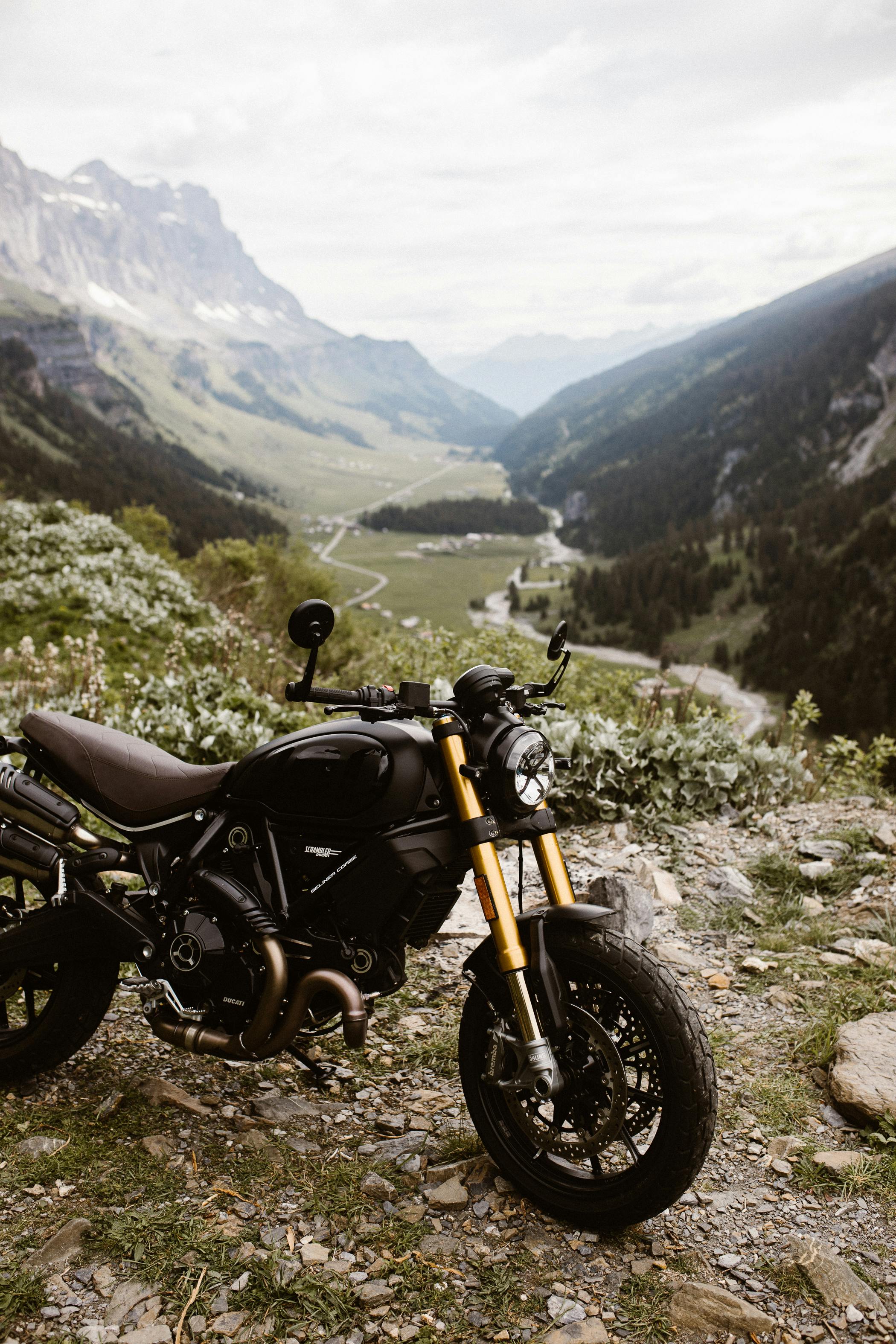 A Ducati Scrambler motorcycle parked against a breathtaking mountain landscape, showcasing adventure and freedom.