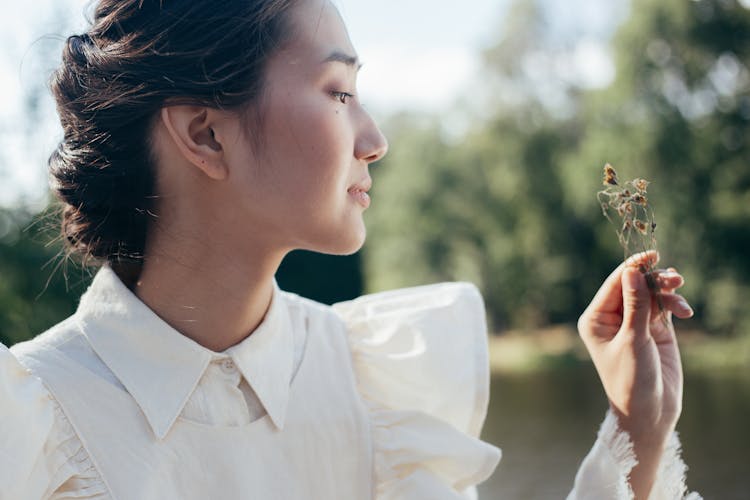 Profile Of Young Woman In White Dress Holding Dried Flowers