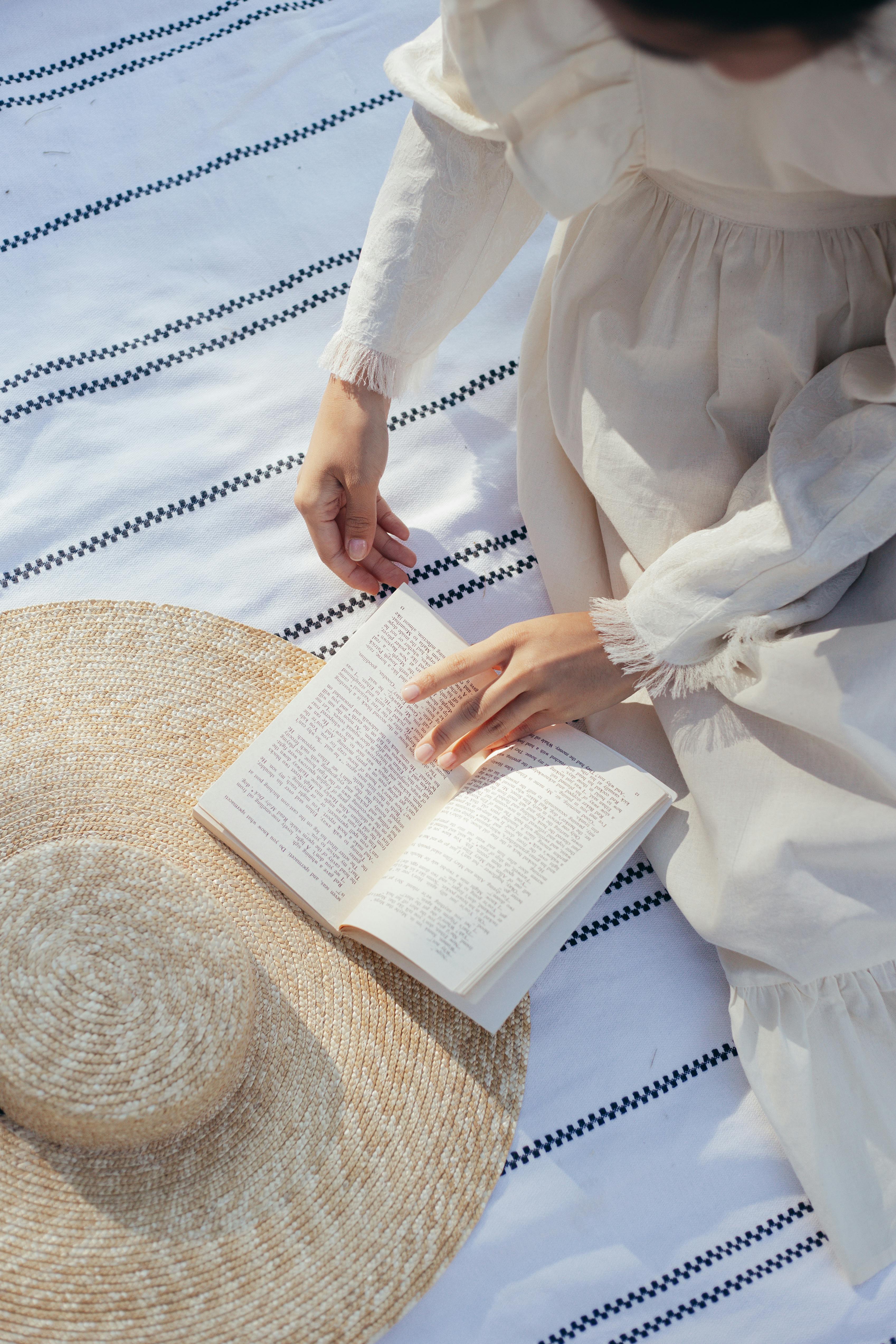 overhead view of woman in white dress reading book