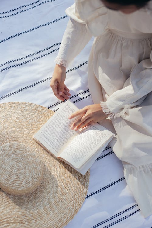 Overhead View of Woman in White Dress Reading Book