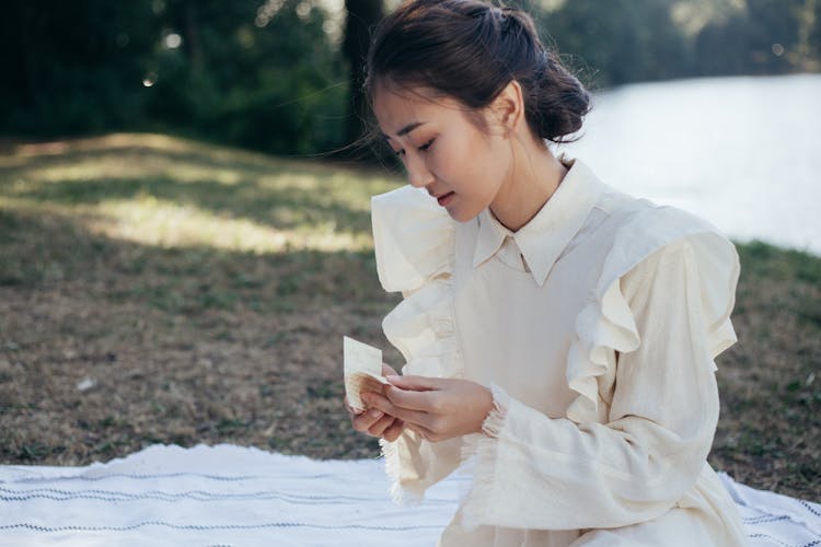 Young Woman In White Dress Holding Letter In Park