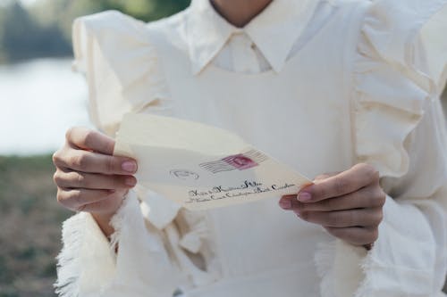 Free Mid Section of Woman in White Dress Holding Letter Stock Photo