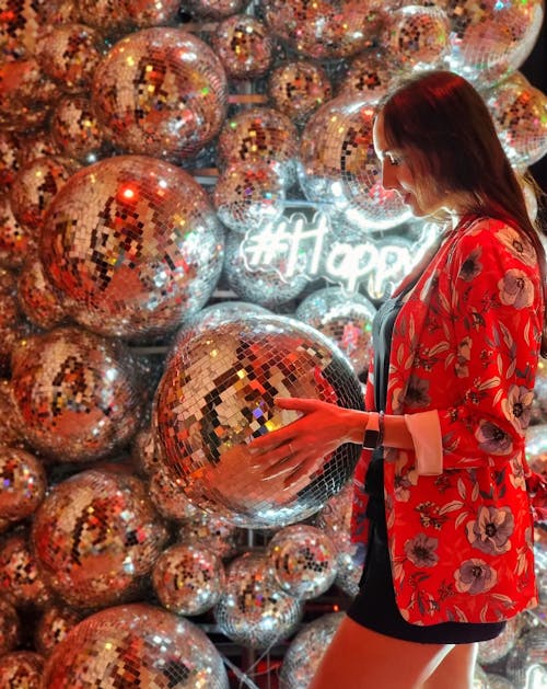 Woman in Red Floral Blazer Holding a Silver Disco Ball 