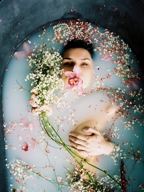 Directly Above View of Woman Lying in Bathtub with Flower on Mouth