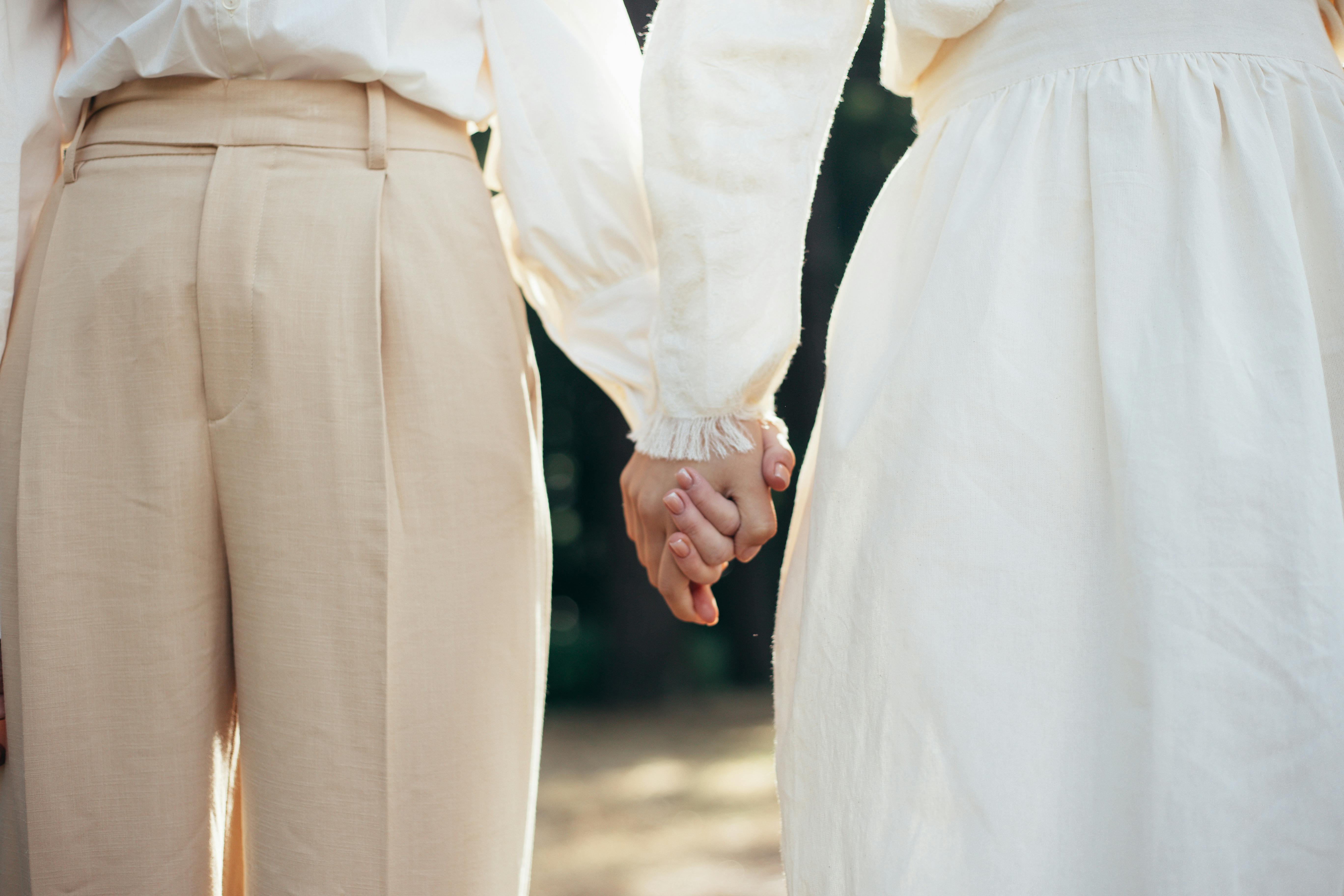 mid section of two women in old fashioned clothing holding hands in park