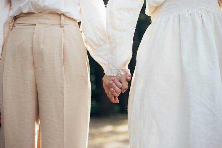 Mid Section Of Two Women In Old-Fashioned Clothing Holding Hands In Park