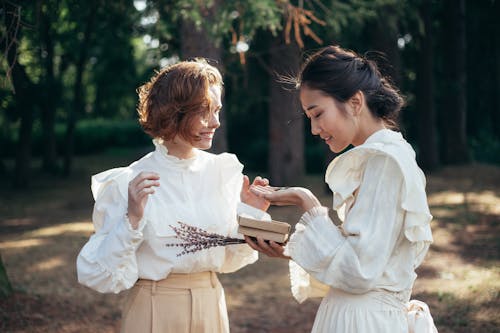 Smiling Women in Old-Fashioned Clothing Looking at Gift in Park