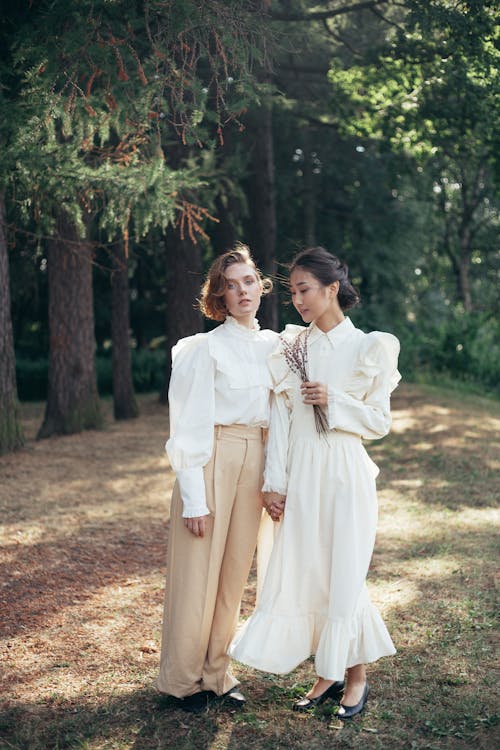 Portrait of Two Women in Old-Fashioned Clothing Holding Hands in Park