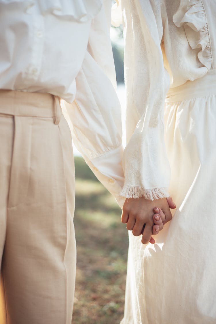 Mid Section Of Two Women In Old-Fashioned Clothing Holding Hands In Park