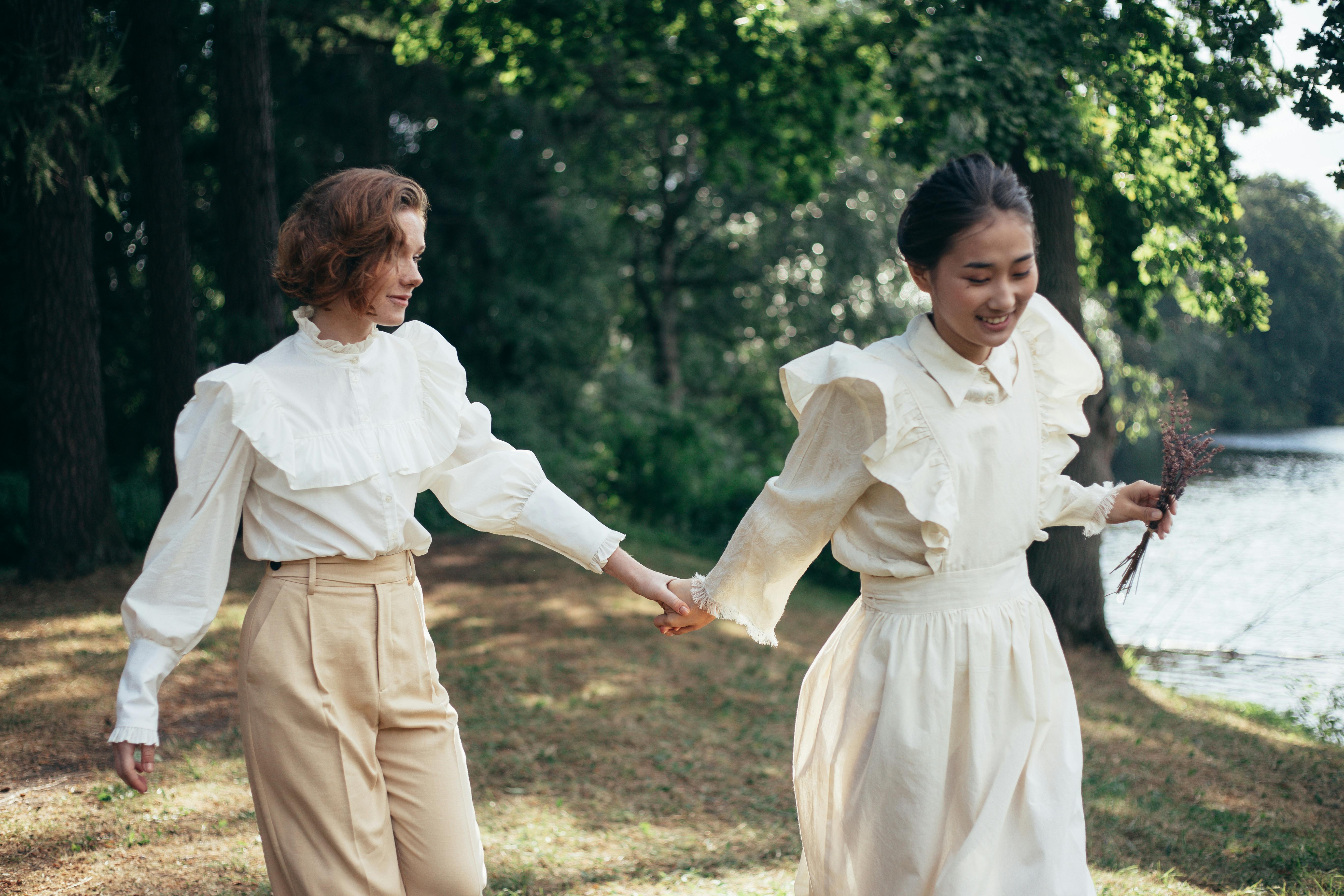 women in old fashioned clothing holding hands in park