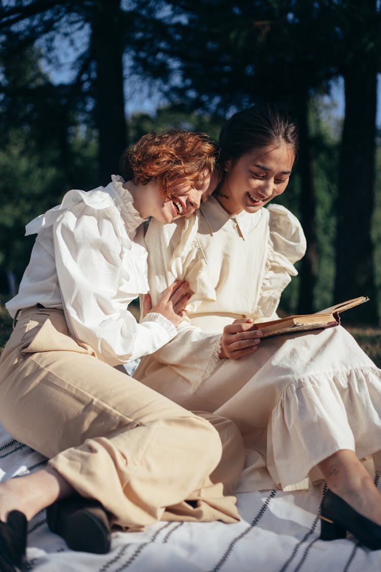 Smiling Women In Old-Fashioned Clothing Reading Book On Picnic Blanket 