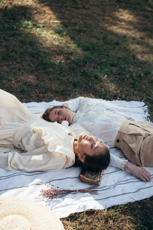 Free Women in Old-Fashioned Clothing Lying on Picnic Blanket Stock Photo