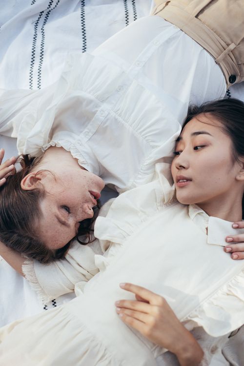 Free Two women lying on a blanket, sharing a tender moment outdoors. Stock Photo