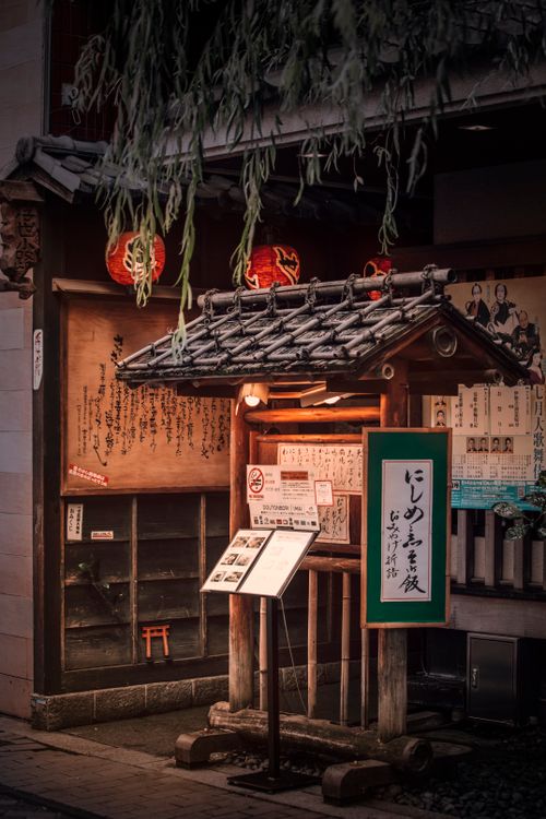 Free Cozy exterior of a traditional Japanese restaurant adorned with lanterns and wood paneling. Stock Photo