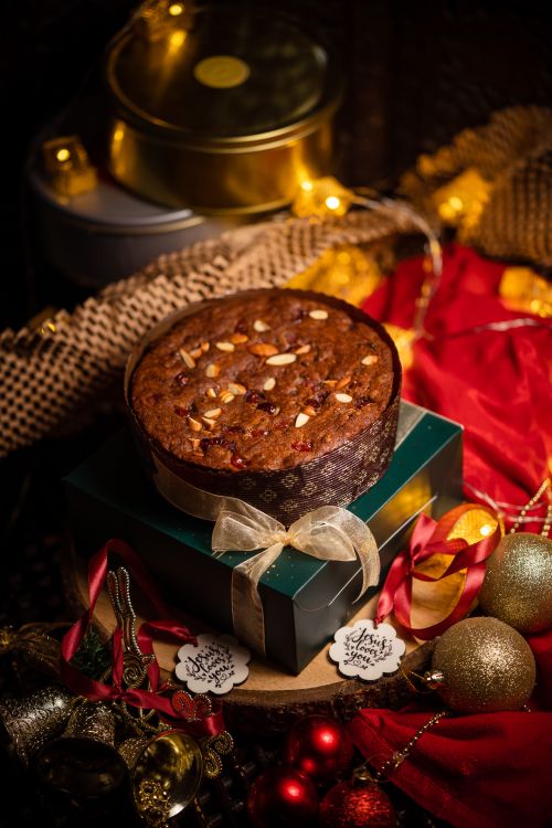 Free Delicious Christmas fruit cake surrounded by festive ornaments and decorations, perfect for holiday celebrations. Stock Photo