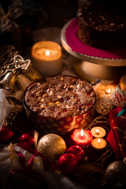Free A beautifully decorated Christmas cake surrounded by festive candles and ornaments. Stock Photo