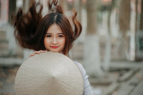 Selective Photography of Woman Holding Conical Hat