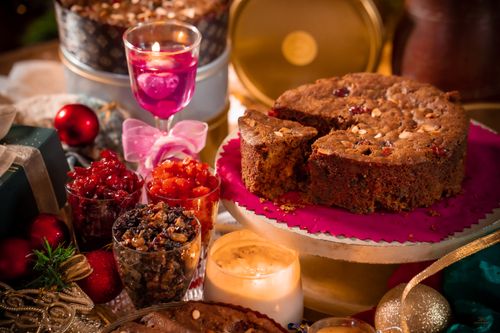 Free Delicious festive fruit cake surrounded by Christmas decorations and candles, perfect for holiday celebrations. Stock Photo