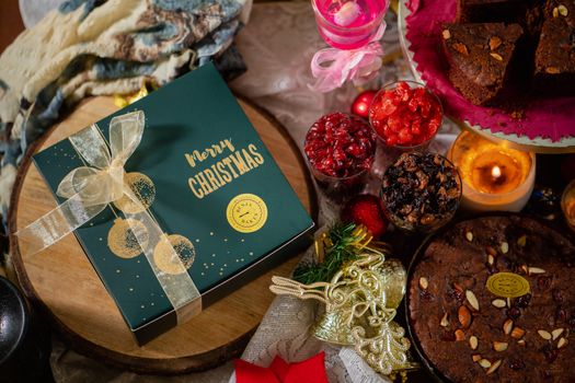 A delicious Christmas celebration with cakes, a gift box, and festive candles.