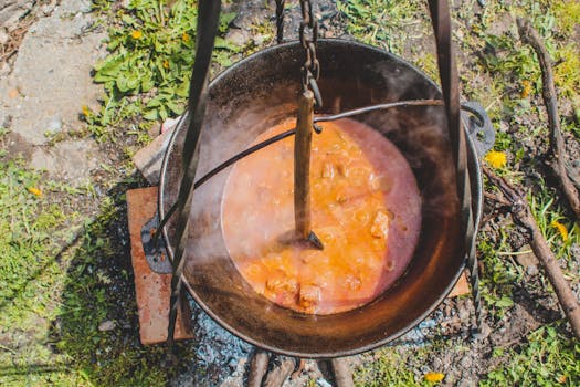Aerial view of a traditional stew being cooked in an iron cauldron outdoors in Romania.