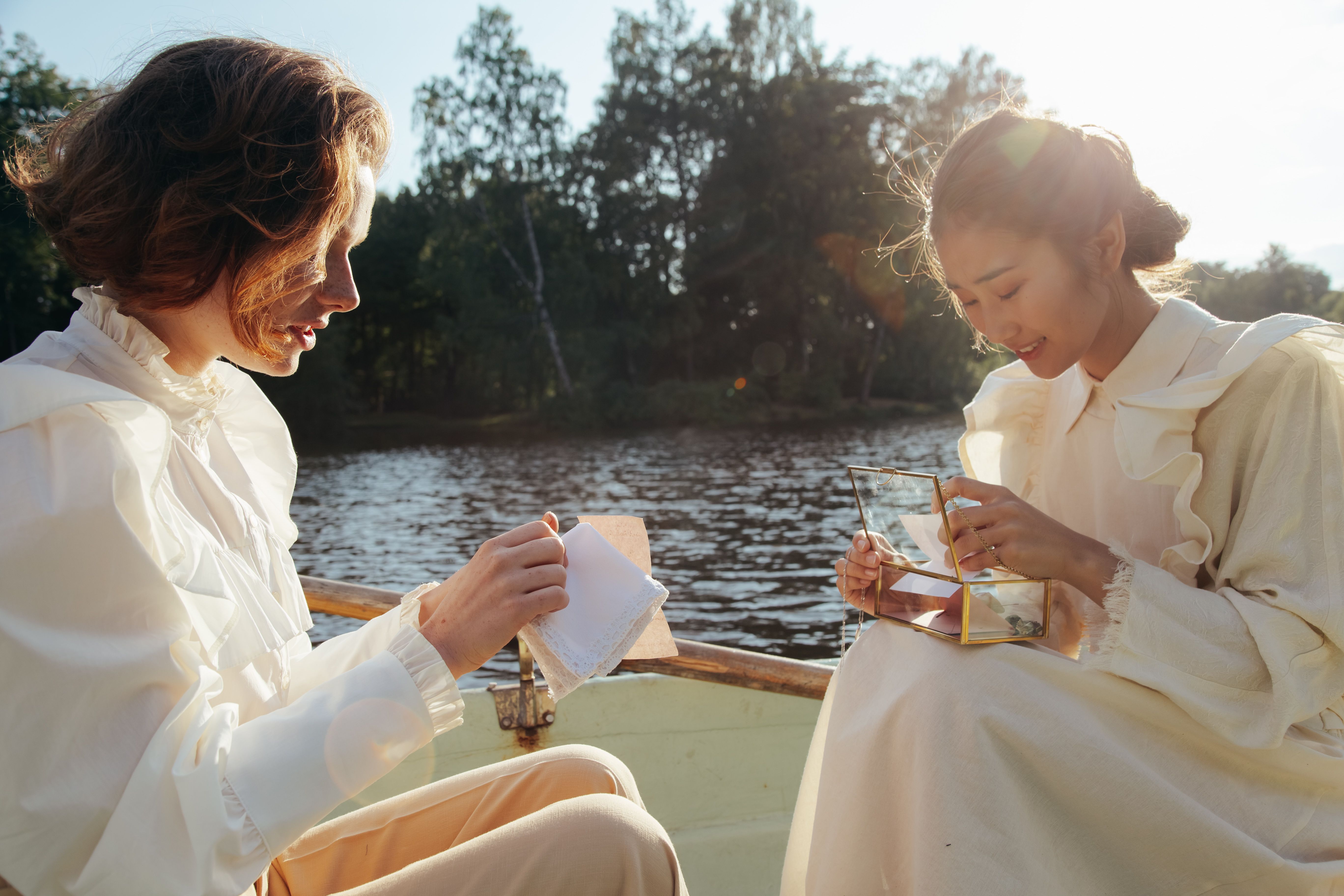 Two women enjoy a calming boat ride, engaged in conversation under the warm sunlight.