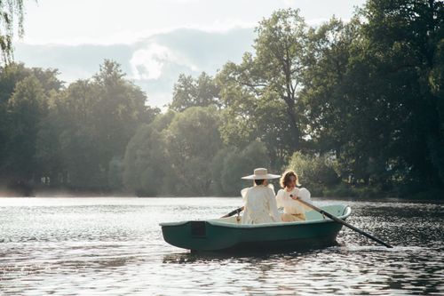 Free Two women enjoy a tranquil boat ride across a misty lake surrounded by trees. Stock Photo