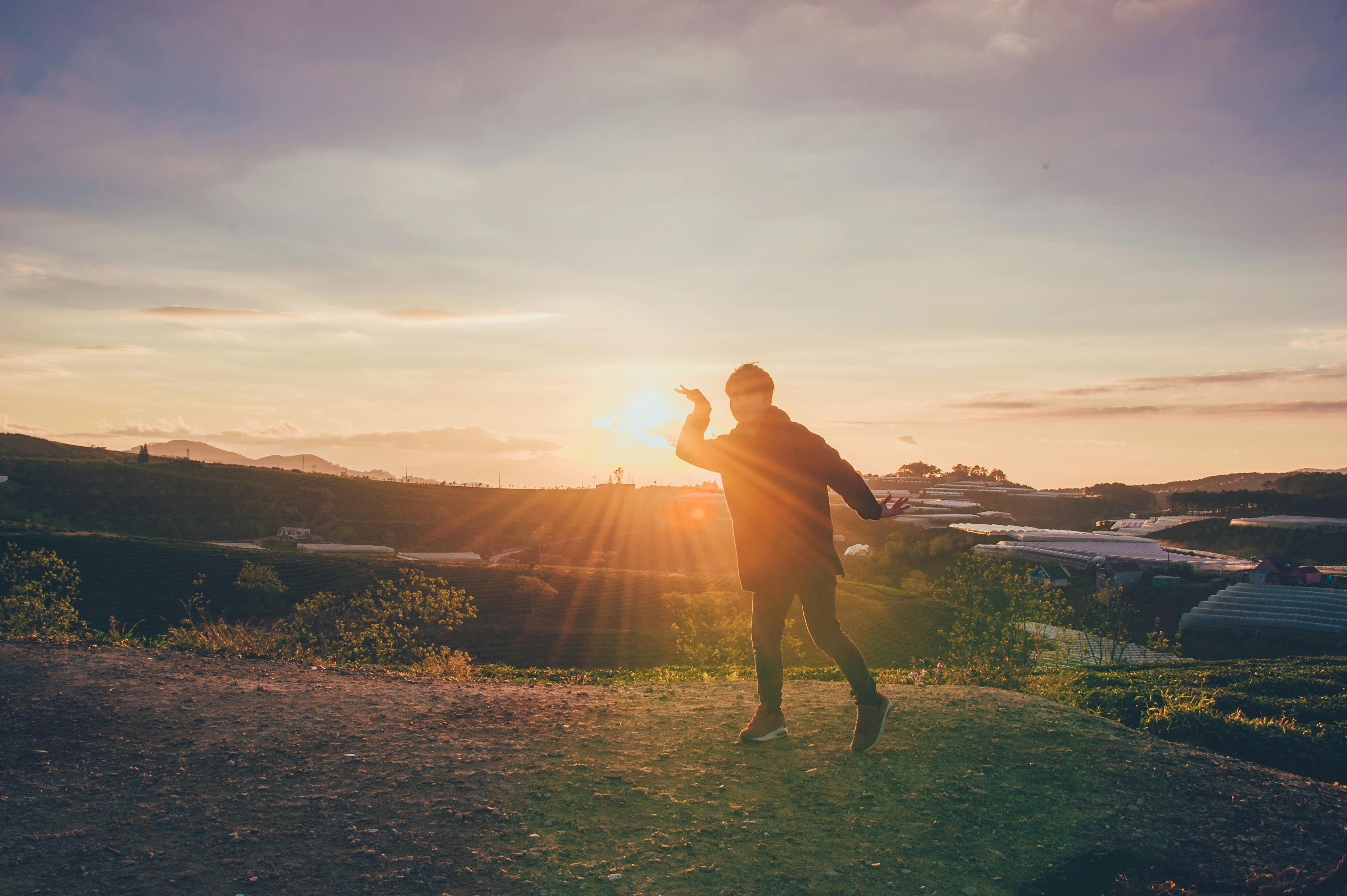 日落时分，一个成年人的舞姿轮廓迷人，山顶的美景尽收眼底