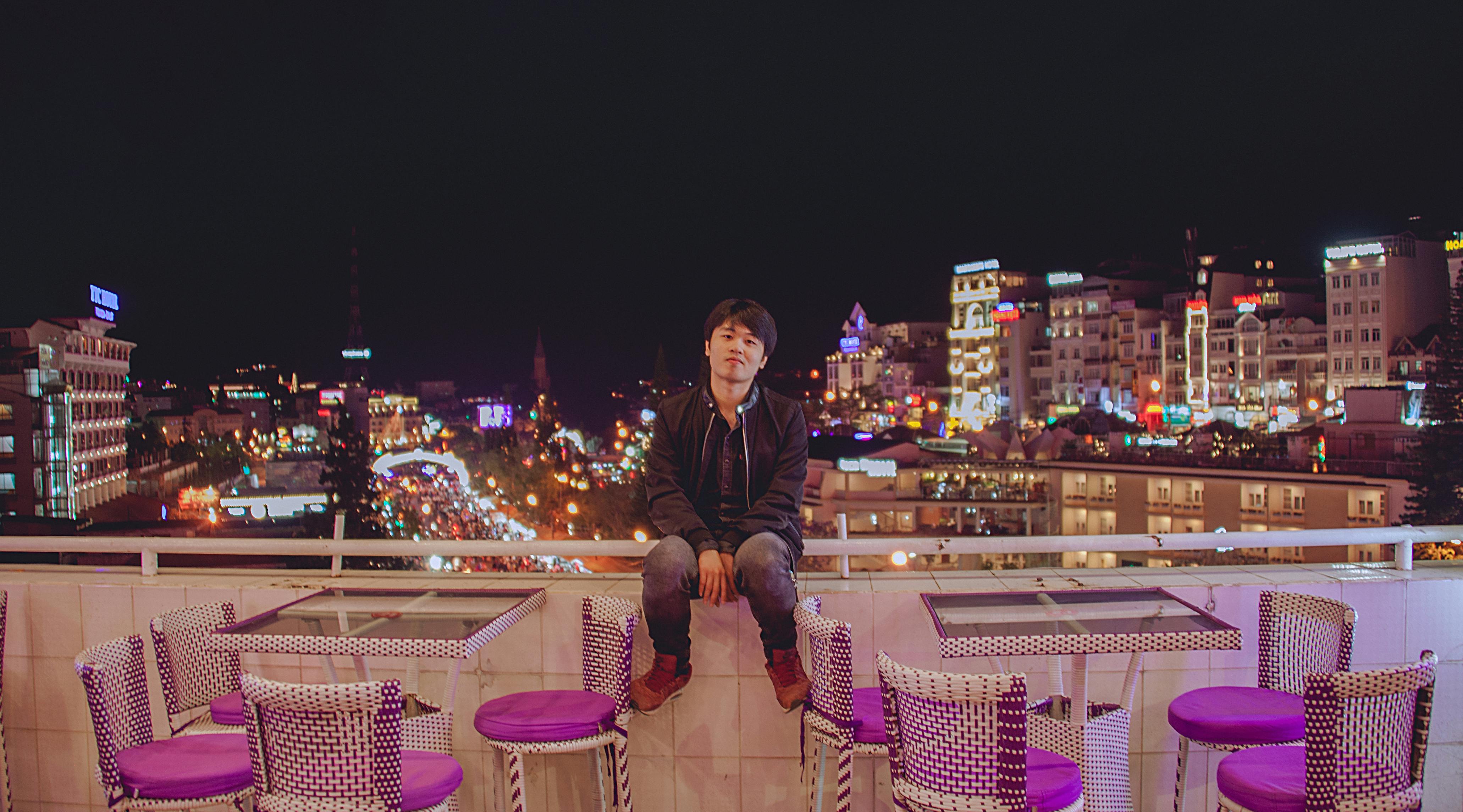 一名亚洲男子在屋顶阳台上，享受着充满活力的城市夜生活