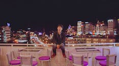 一名亚洲男子在屋顶阳台上，享受着充满活力的城市夜生活