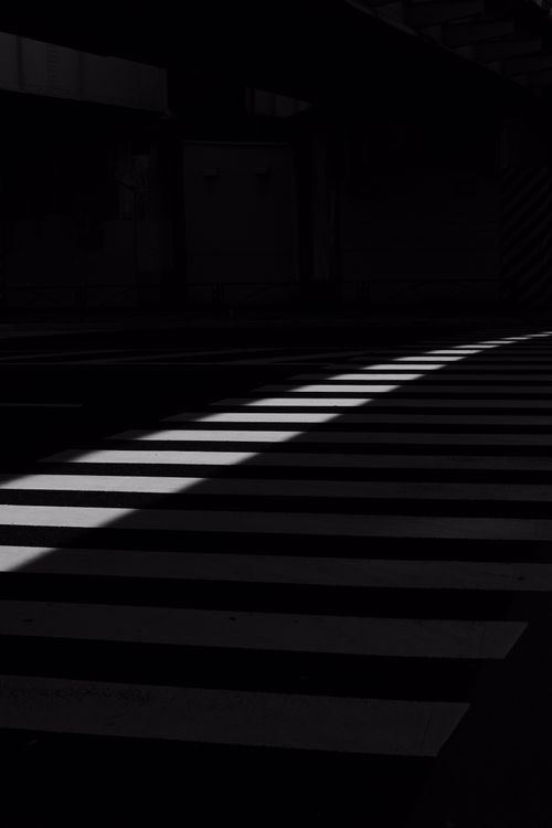 Free High contrast black and white abstract image of a pedestrian crossing with dramatic shadows. Stock Photo
