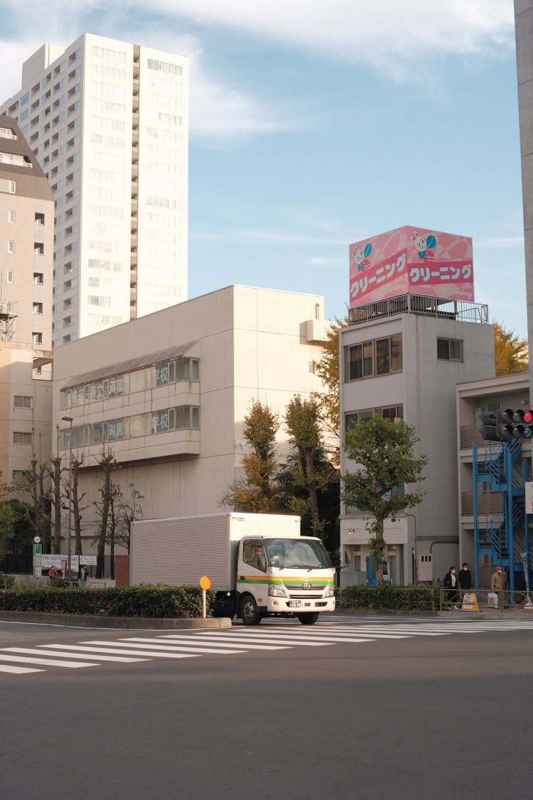 A White Truck Driving Down The Street In The City