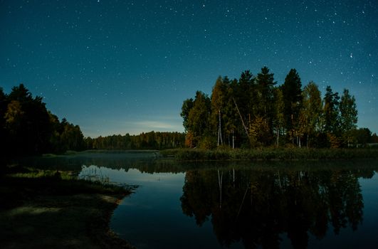 A serene night scene of a starry sky over a tranquil forest lake in Russia.