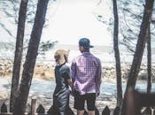 在越南胡志明市，一对夫妇并肩而立，透过树丛欣赏着海滩的风景