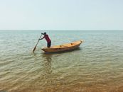 Man in Black Shirt and Black Shorts Riding Brown Wooden Boat on Sea