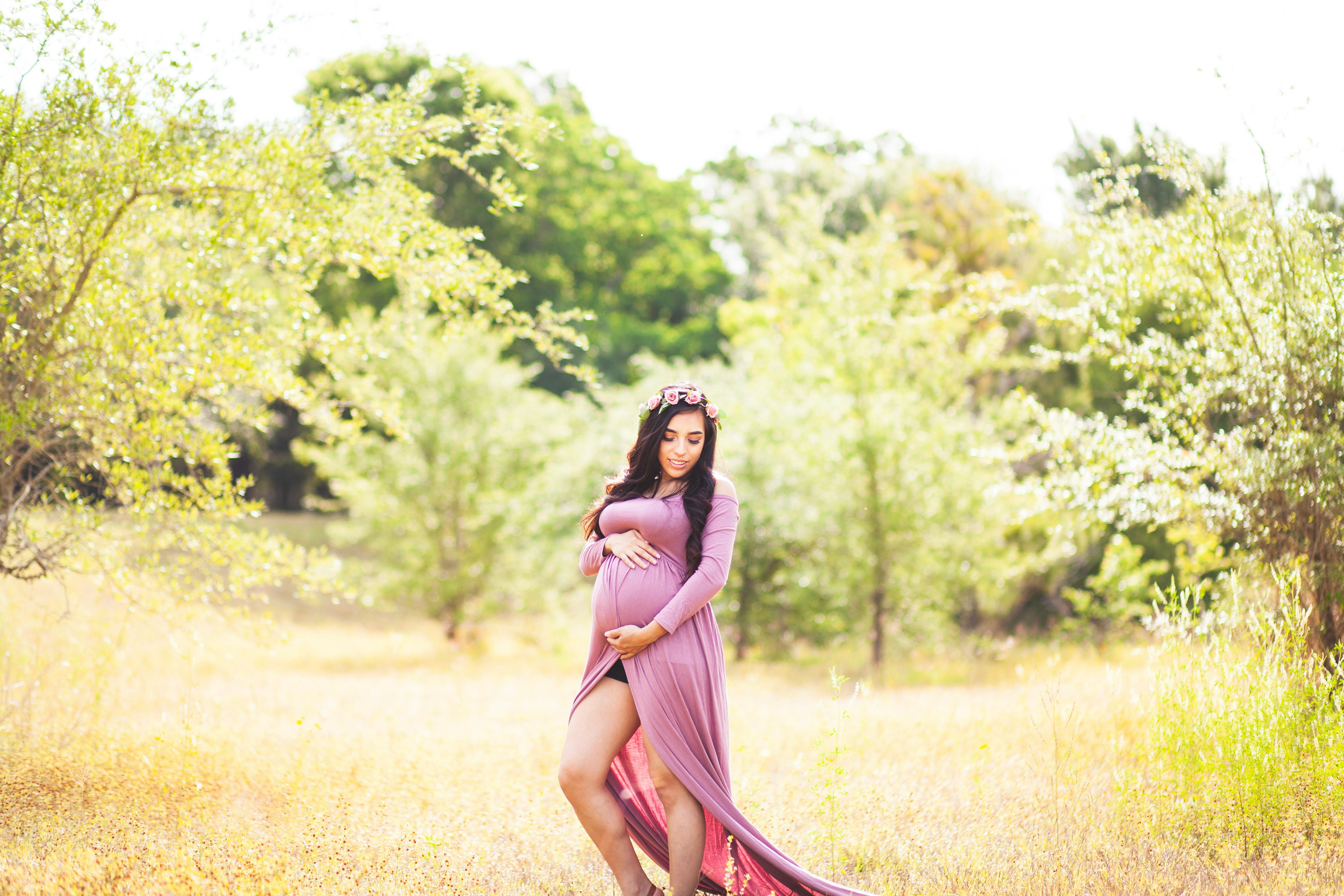 woman standing on grass field surrounded with trees