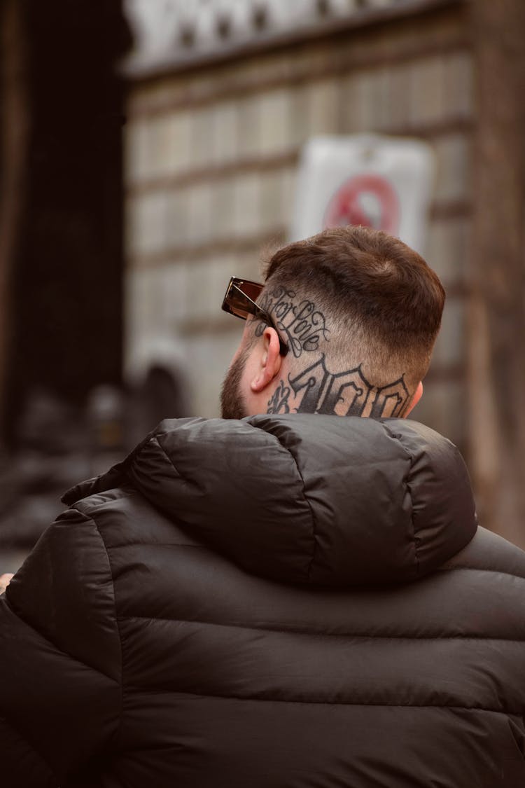 A Tattooed Man Wearing A Puffer Jacket 