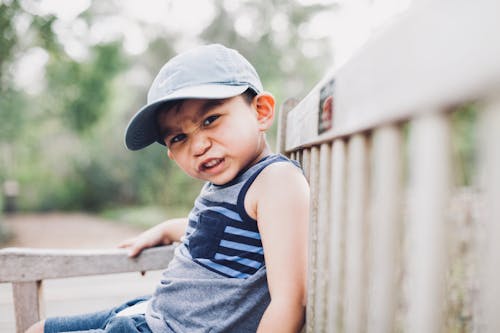 Shallow Focus Photography Of A Boy Sitting On Bench