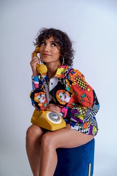Vibrant studio portrait of a woman with a retro yellow rotary phone.