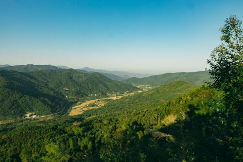 Free Beautiful scenic view of a lush green mountain valley under a clear blue sky. Stock Photo
