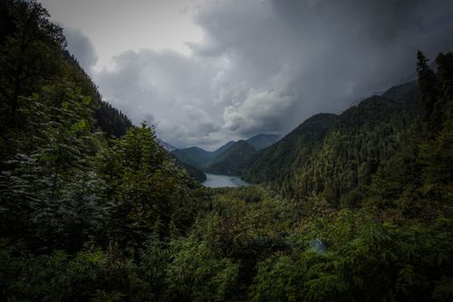 Free Stunning aerial view of lush green mountains, peaceful river, and dramatic clouds. Stock Photo