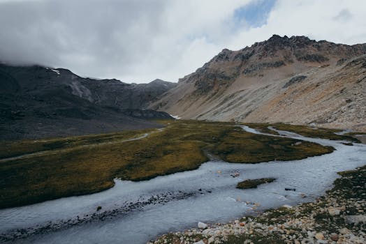 Breathtaking mountain landscape with a meandering frozen stream under a cloudy sky.