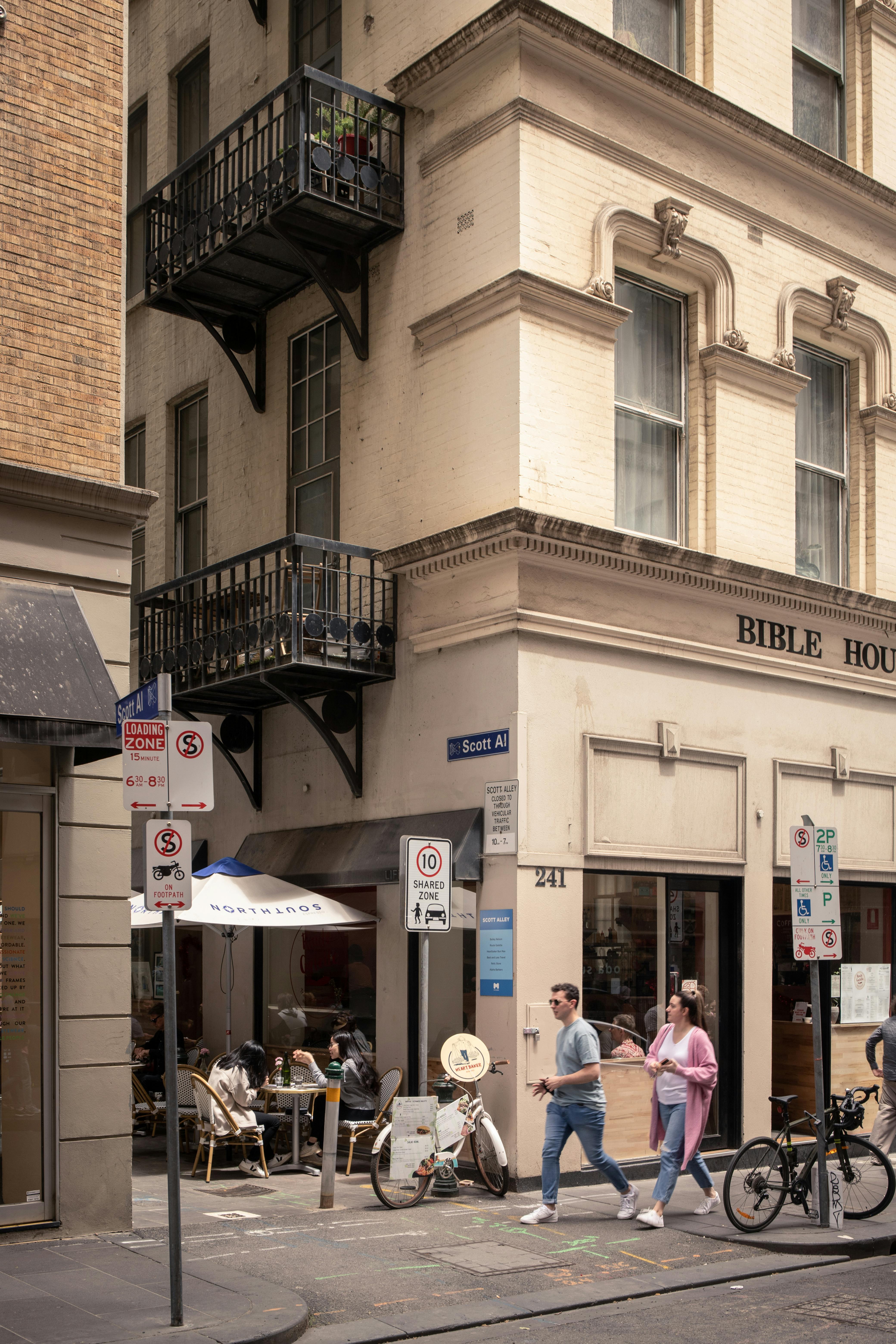 A busy Melbourne street scene with pedestrians near the historic Bible House in daylight.