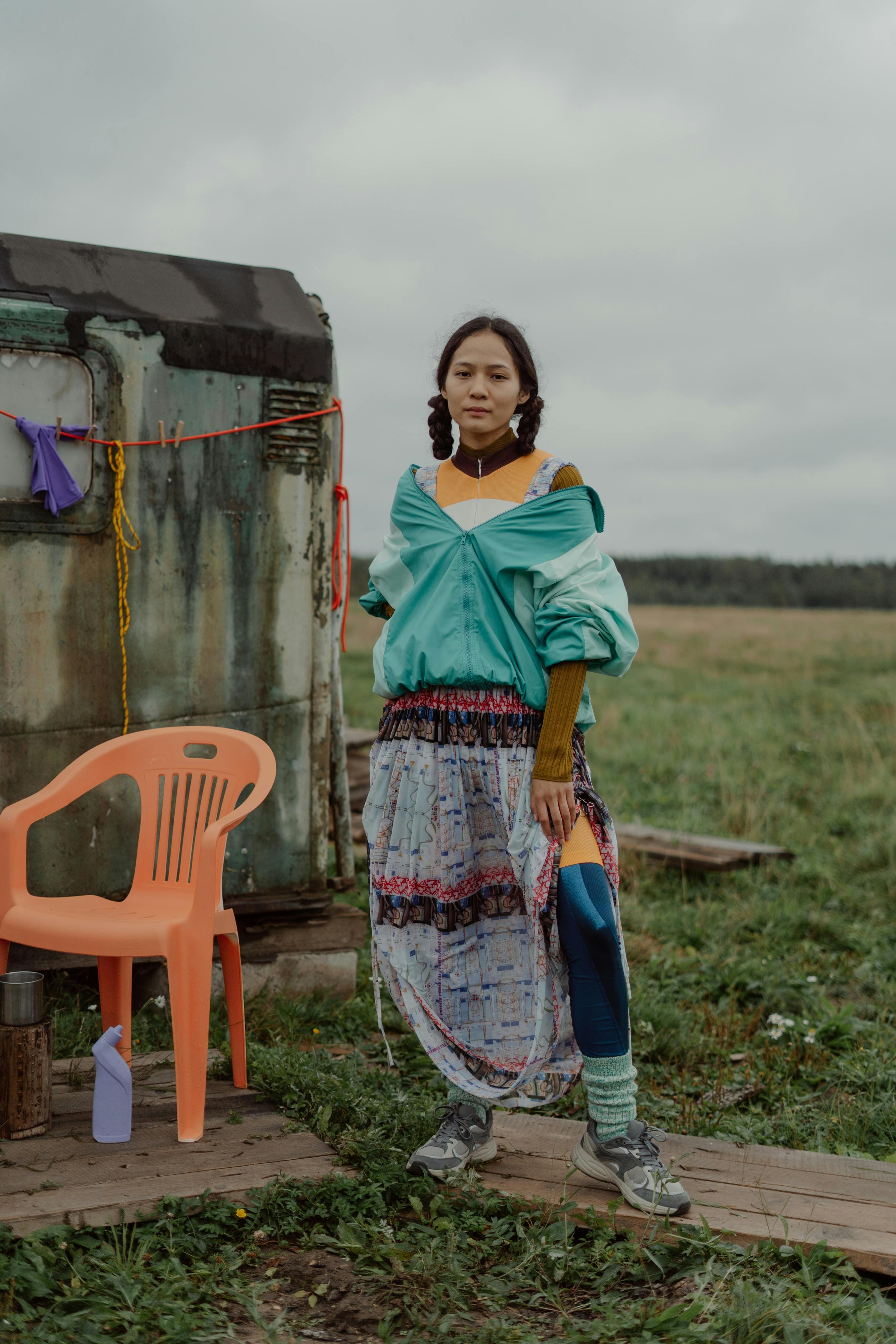 woman in skirt standing by shed on grassland