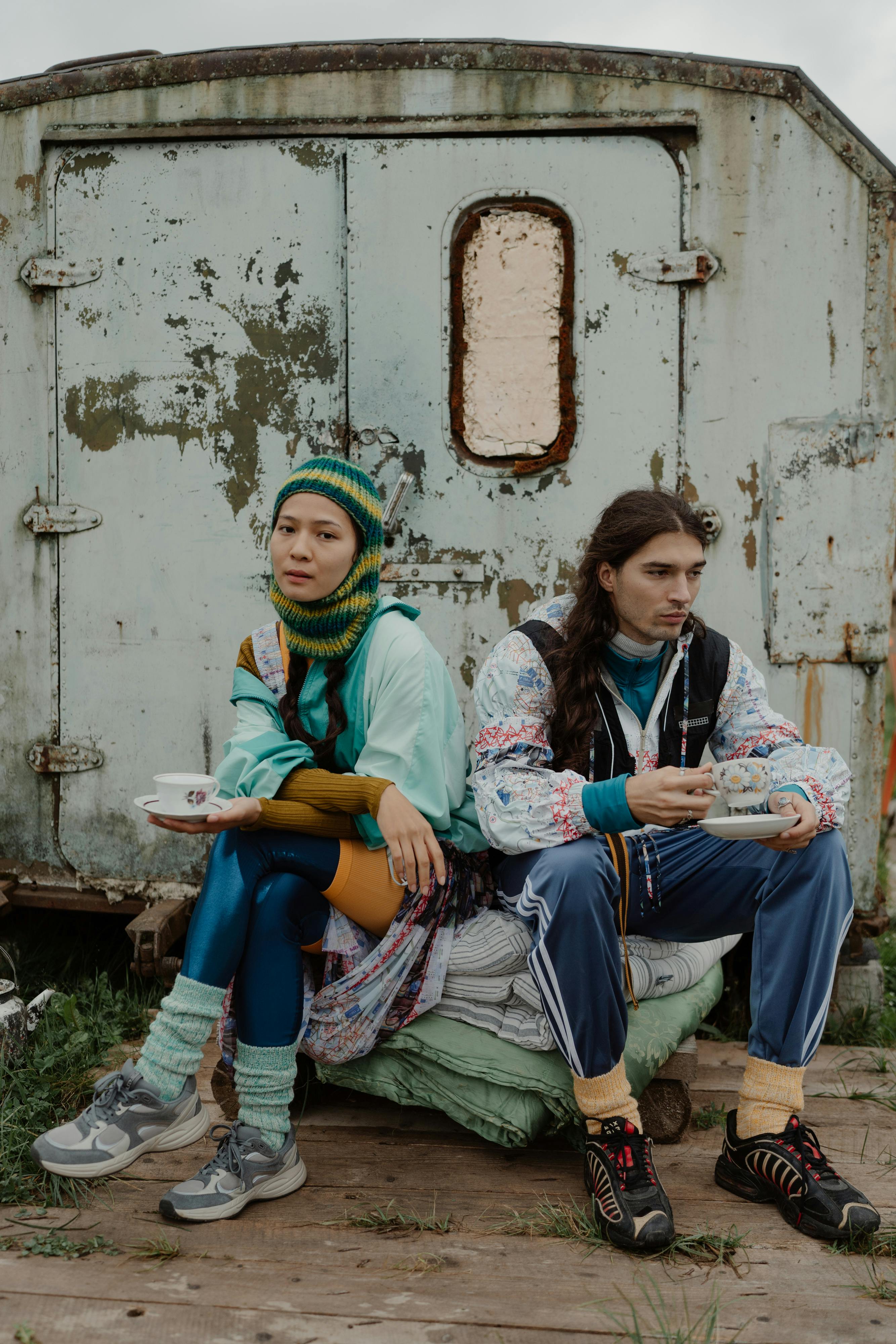 A young couple enjoys tea outdoors in a retro setting against a rustic background.
