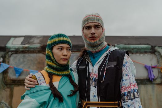 A couple in vibrant knitwear posing confidently outdoors, showcasing unique fashion style.