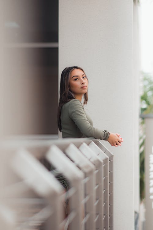 Free A Woman in Long Sleeves Leaning on the Metal Railings Stock Photo