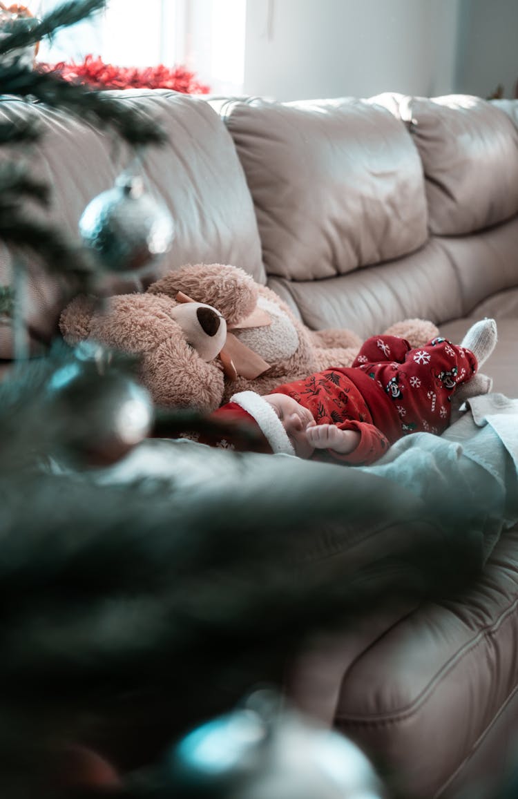 Baby In Red Clothes And Santa Hat Sleeping On Couch