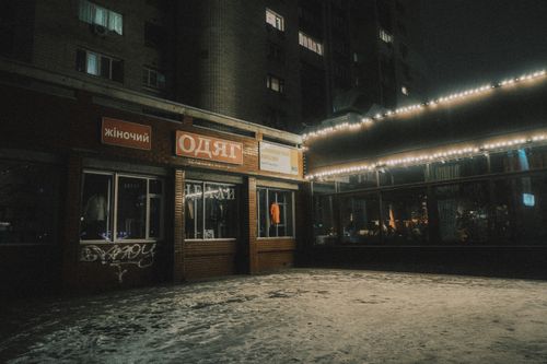 Free A dimly lit clothing store with winter snow at night, evoking a cozy urban mood. Stock Photo