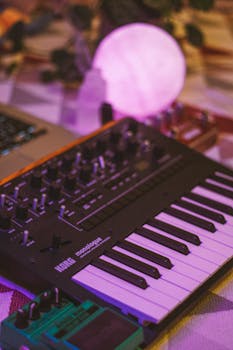 A Korg synthesizer illuminated with purple ambient lighting on a table setup.